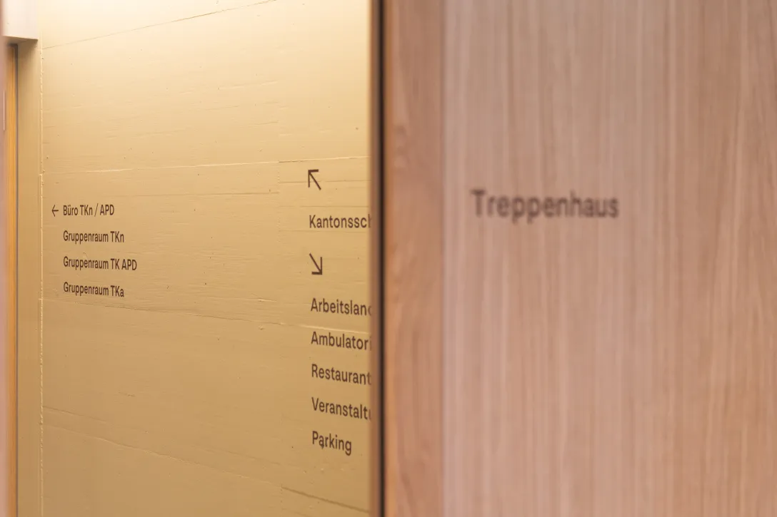 Treppenhaus, Türe, Holz, Eiche, gelbe Betonwand, Signaletik